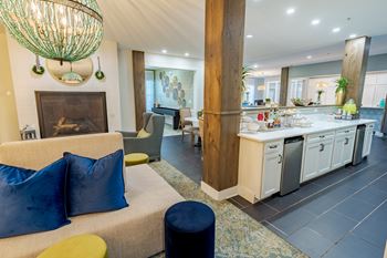 A modern living room with a fireplace and a kitchen area in the background.